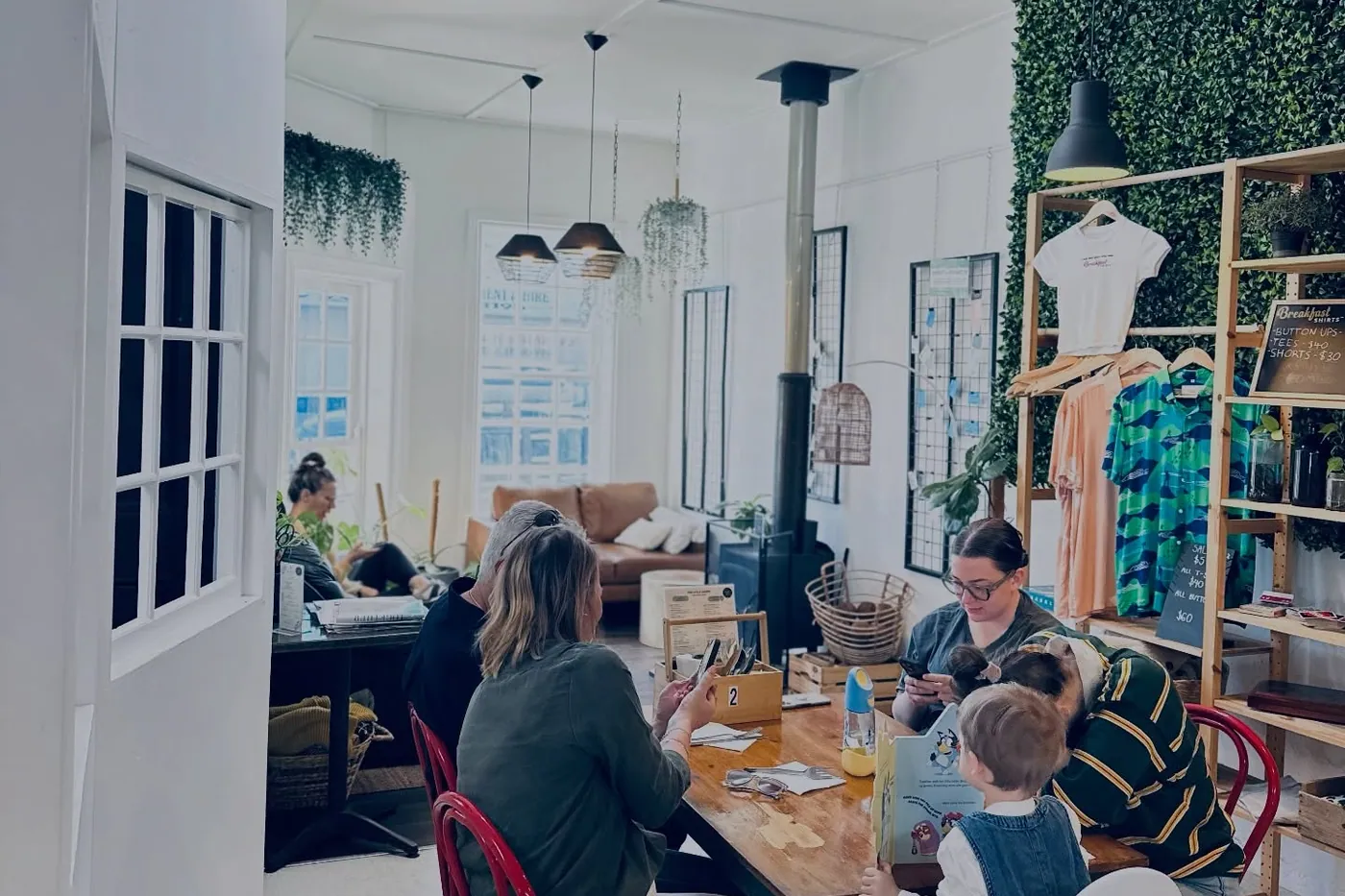 The dining room full — long tables, wood fire, plants along the wall