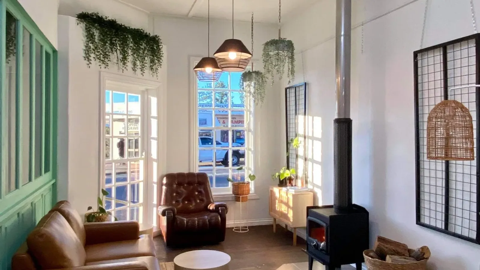 The lounge area at The Little Larder — armchairs, plants and a wood-fired heater