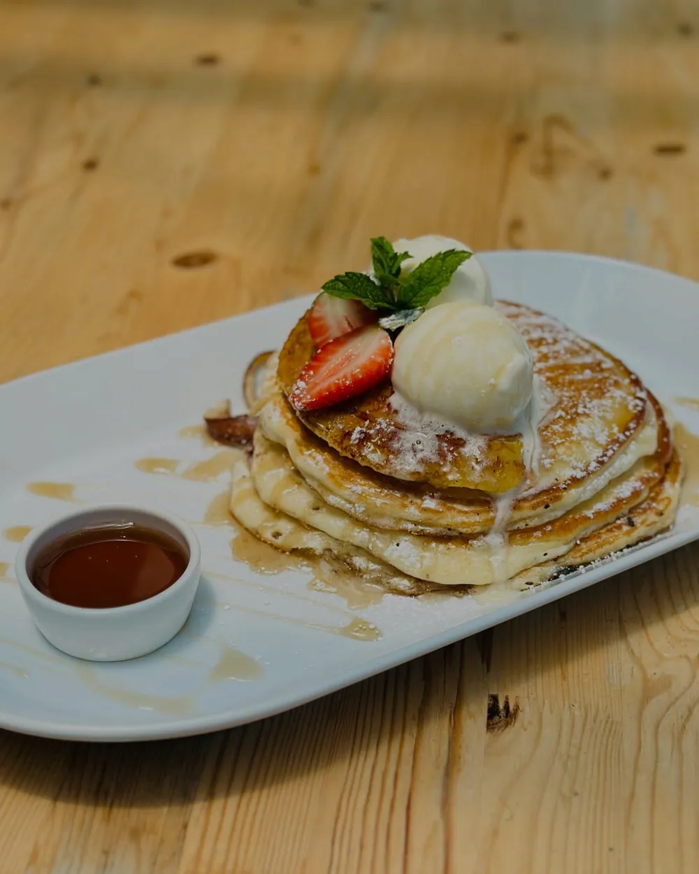 Pancakes with ice cream and strawberries, maple syrup alongside
