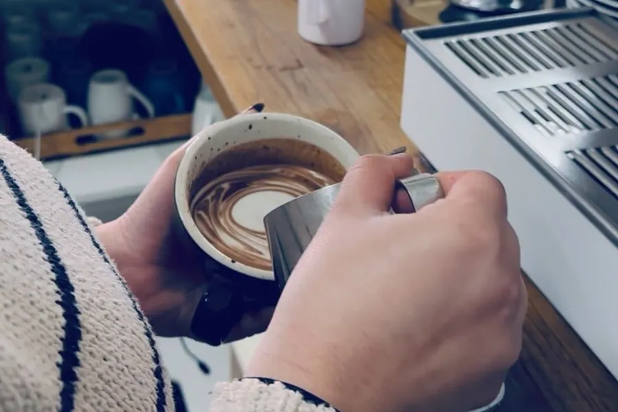 Two hands wrapped around a coffee at the counter